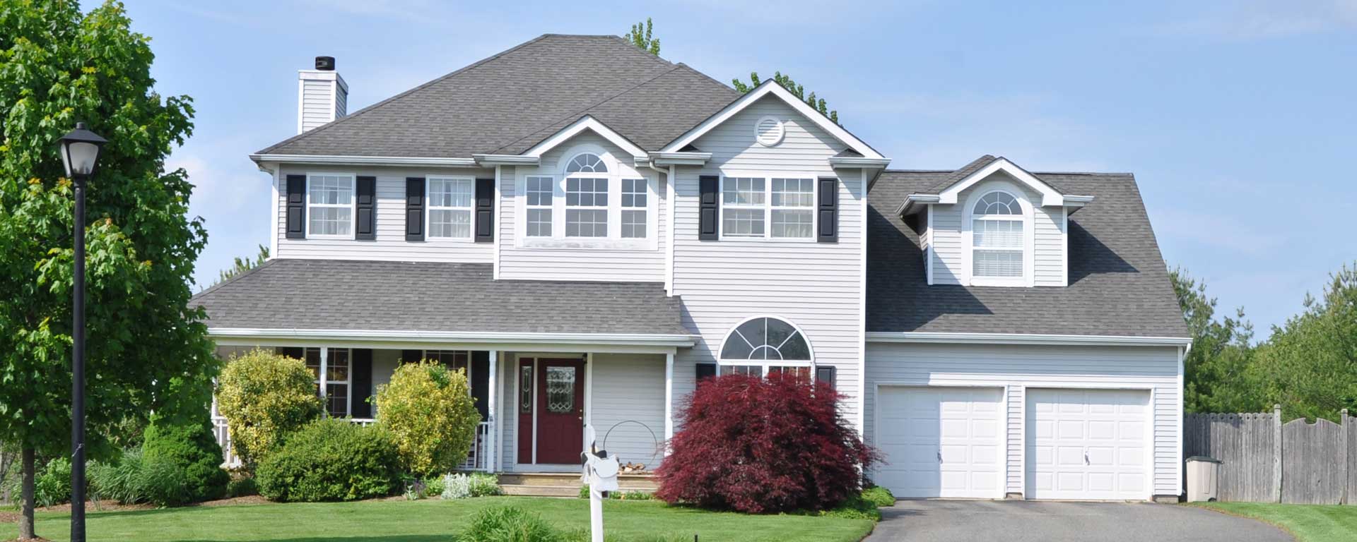 A large residential home with a well-kept lawn and a two-car garage.